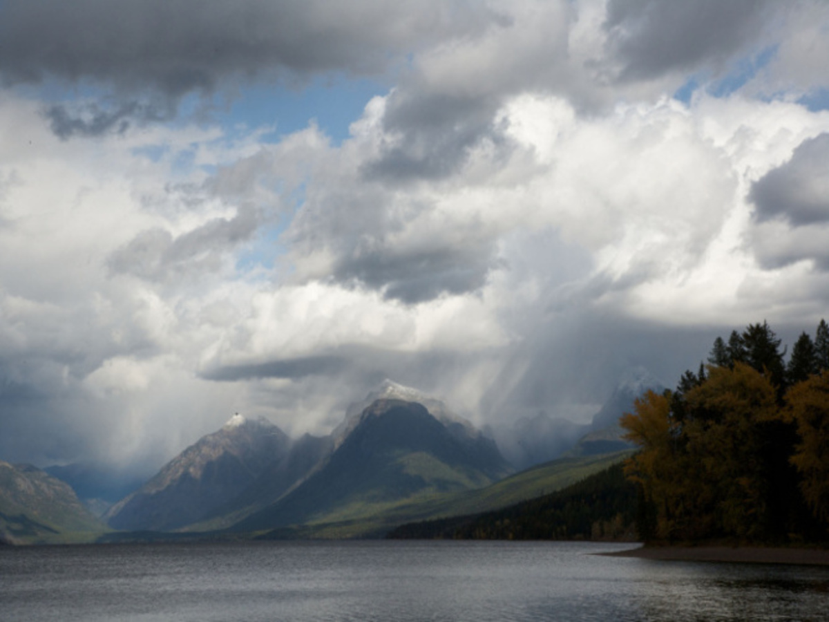The unchanged Lake McDonald input photo: mountains, clouds and a wooded lakeshore.